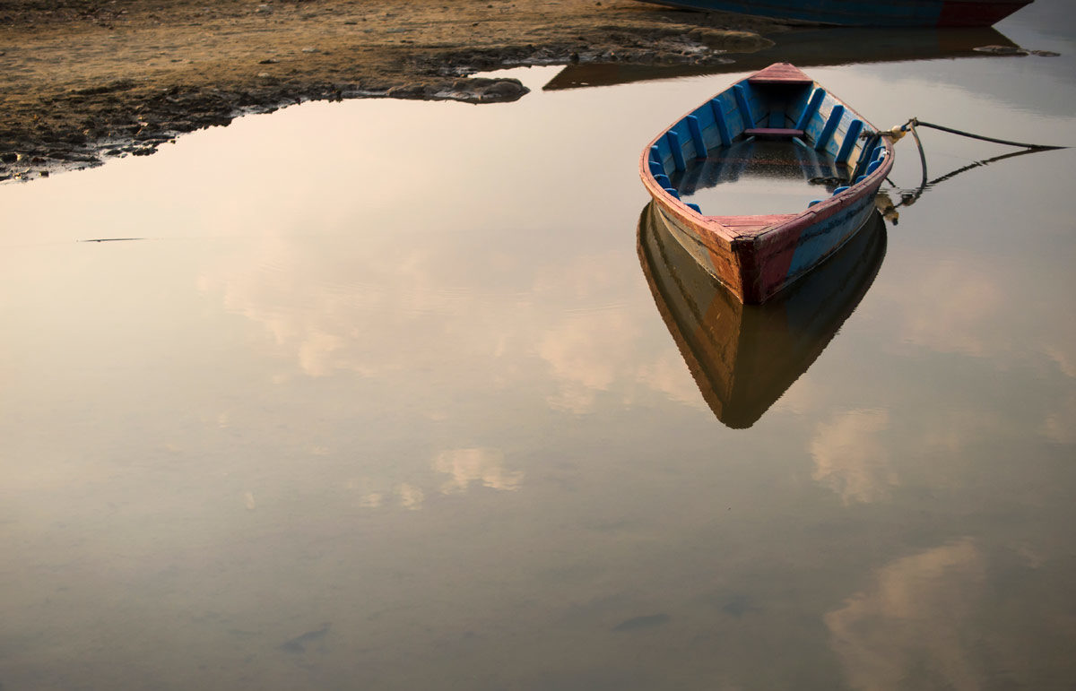 Photo of rowboat floating on still waters of a lake by rmnunes via iStock